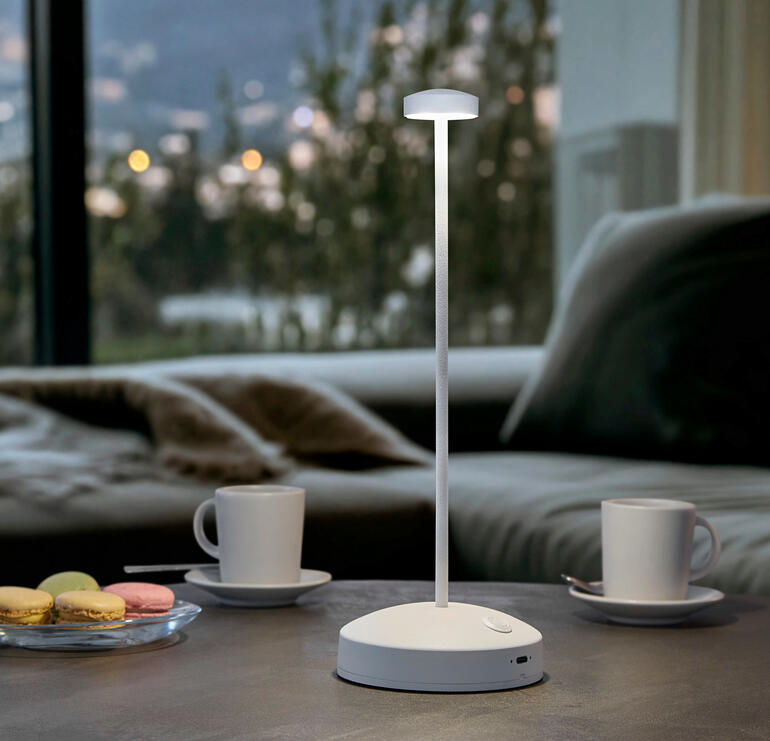 Blanc Lampe de table design avec batterie, couleur : blanche, sur une table avec des boissons.