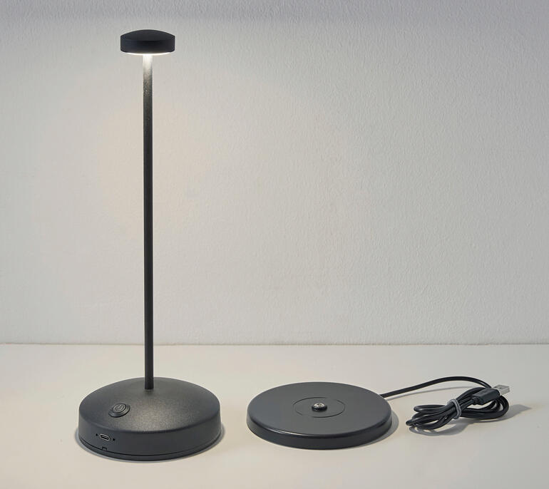 Lampe de table design avec batterie en noir, éteinte sur la table.
