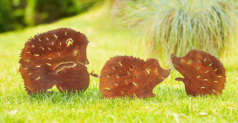 Trois piquets de jardin en forme de hérisson, en métal, sur une pelouse verte.