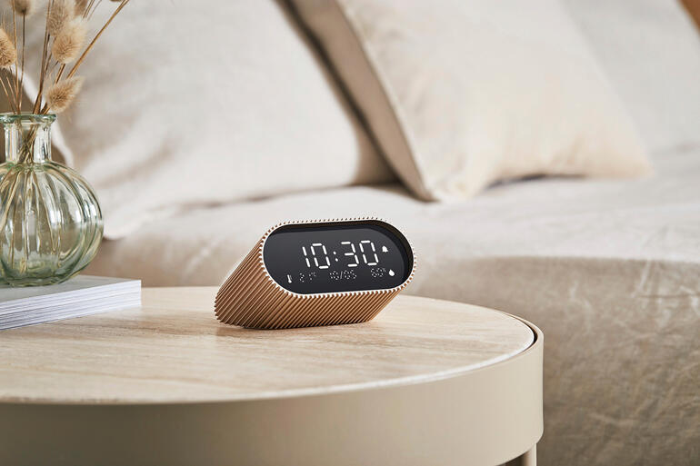 Femme portant une stola plissée noire souriant sur une place.