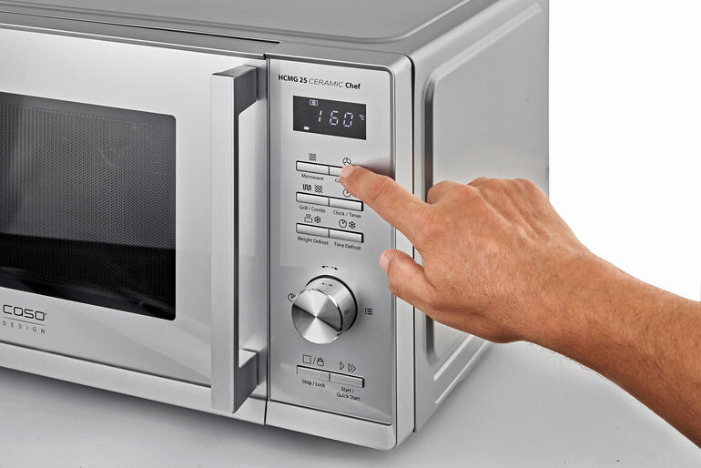 Vous sélectionnez le programme de cuisson souhaité en appuyant simplement sur une touche – et le système automatique intelligent exécute parfaitement la préparation. Main appuyant sur le panneau de commande d'un micro-ondes 3 en 1.