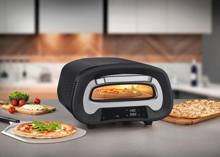 Four à pizza à 430 °C sur un plan de travail, entouré d'ingrédients