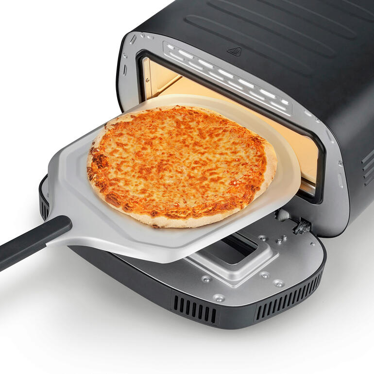 Pizza sur une pelle à pizza, en train d'être mise dans le four à pizza à 430 °C