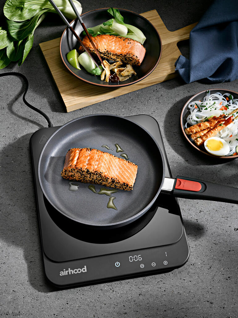 Plaque à induction ultra fine avec une poêle et du saumon grillé.