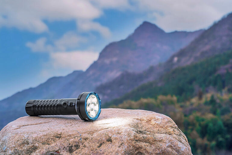 Lampe de poche bidirectionnelle de 5000 lumens sur une pierre avec un paysage montagneux.