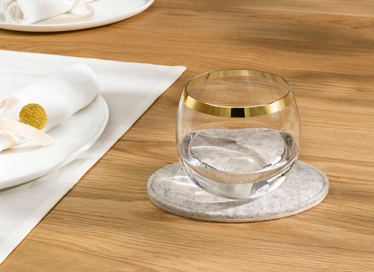 Verre d'eau sur un tapis en feutre gris.