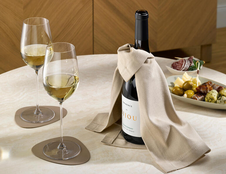 Cape à vin avec une bouteille de vin et deux verres sur une table.
