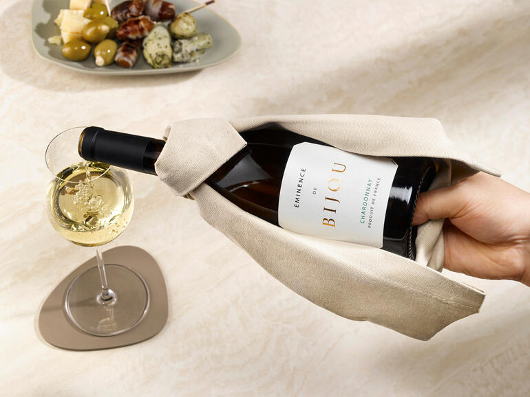 La bouteille tient bien dans la main lors du service – et rien ne coule sur la table. Main prenant une bouteille de vin dans la cape à vin.