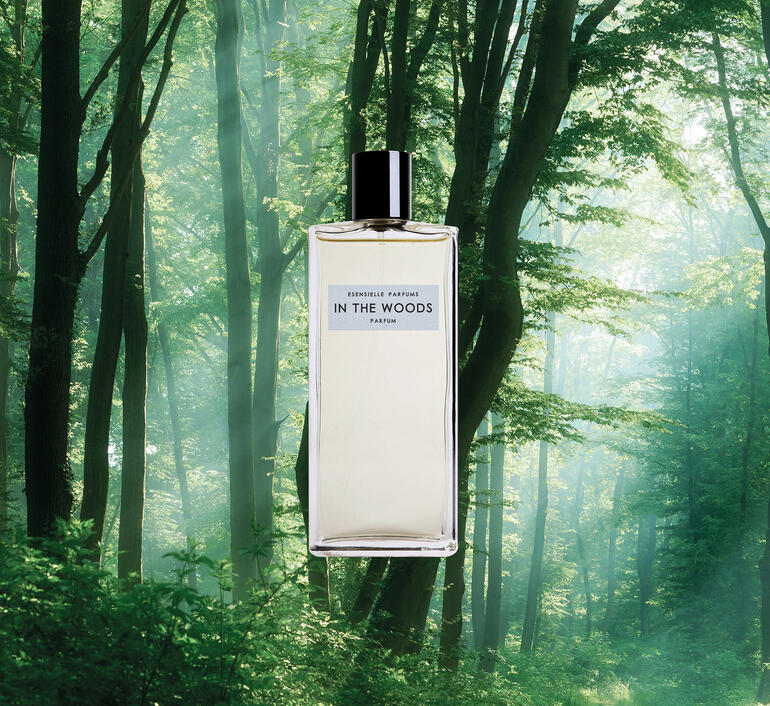 In the Woods Eau de Parfum en spray, 100 ml Bouteille In the Woods Eau de Parfum devant un paysage boisé.