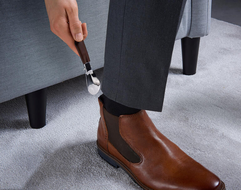 Personne utilisant un embauchoir pliable en cuir de harnais.