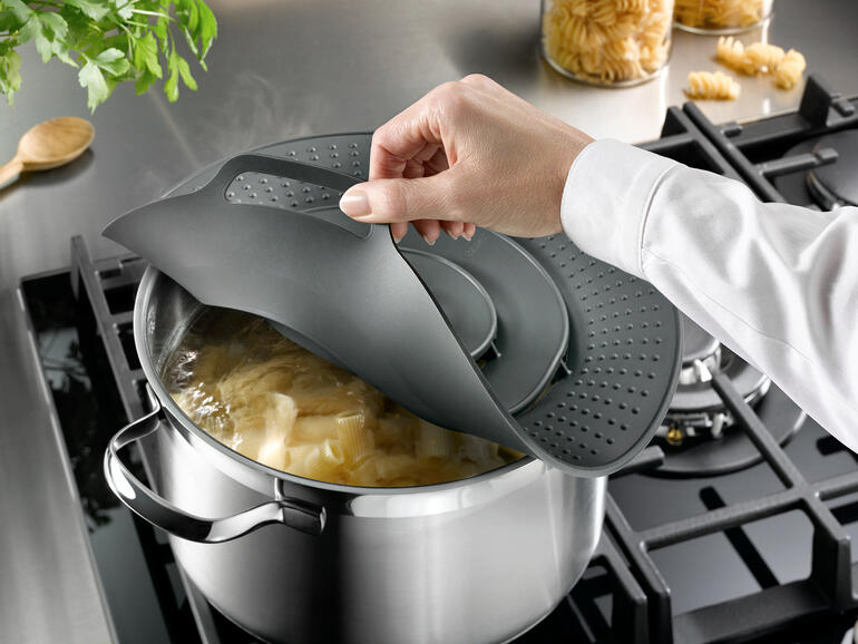 La protection anti-débordement de haute qualité maintient votre cuisinière propre. Personne fixant un couvercle anti-éclaboussures sur une casserole.
