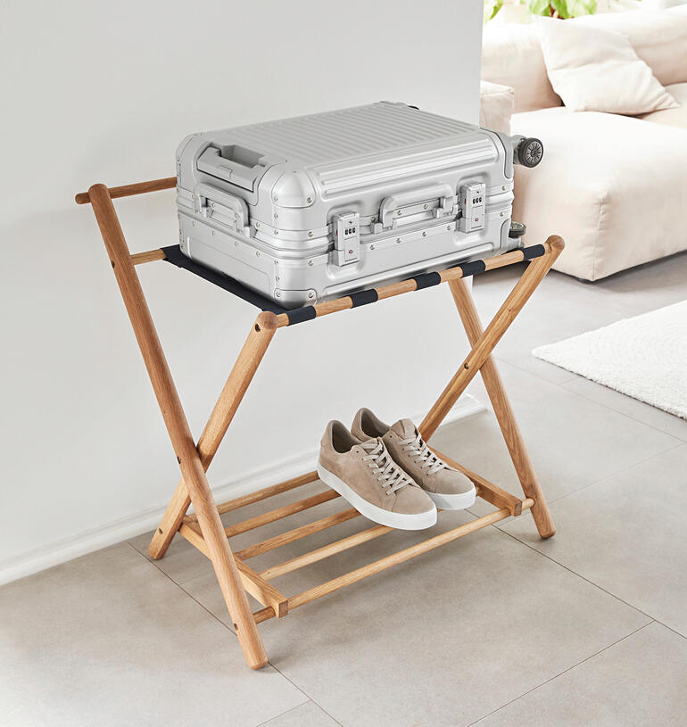Support de bagages en chêne avec bagages à main et chaussures sur un cadre en bois.