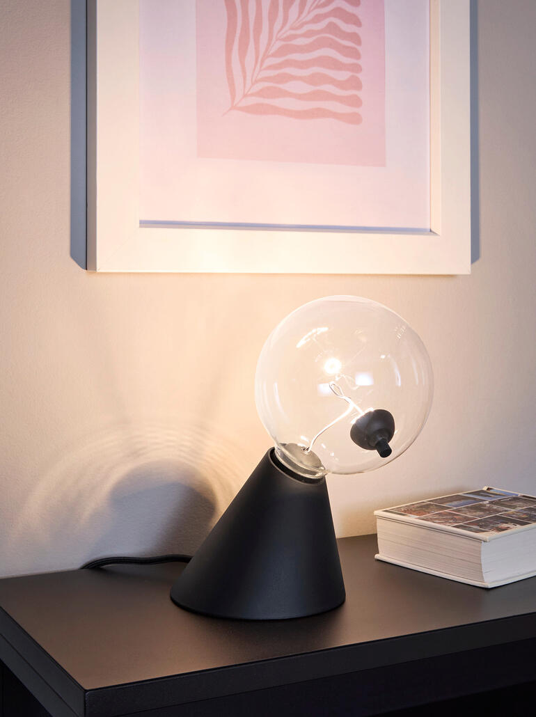Lampe de table Satellite avec un globe en verre transparent et une base noire sur une étagère.