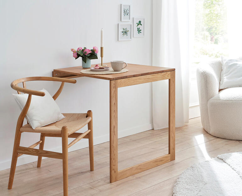 Table murale pliable en bois avec café et fleurs sur la surface.