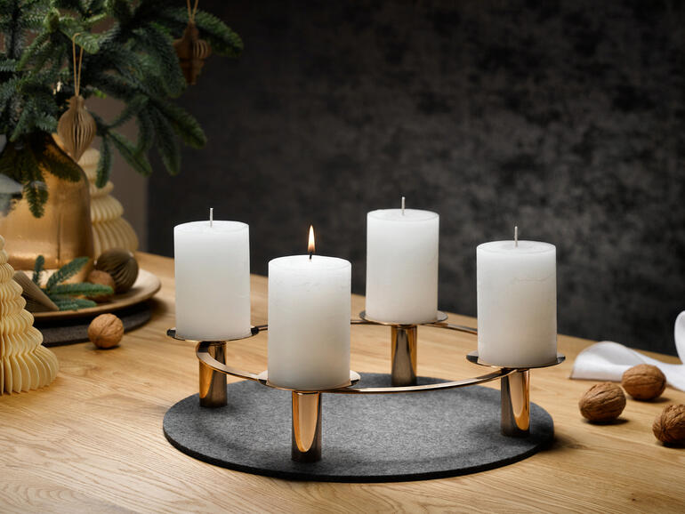 Vous pouvez utiliser le bougeoir variable pour des bougies bâton ou des bougies piliers simplement en le retournant. Bougeoir variable avec quatre bougies blanches sur une table ronde.
