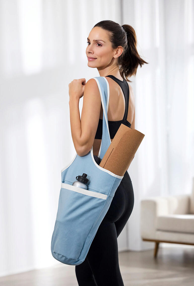 Femme portant un sac de yoga avec un tapis de yoga et une bouteille d'eau.