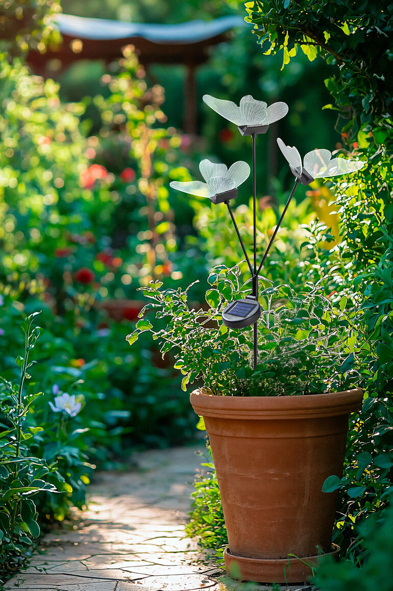 Même durant la journée, les papillons en acrylique presque transparents seront un accroche-regard magique et délicat. Bâton de jardin avec des papillons LED dans un jardin fleuri.