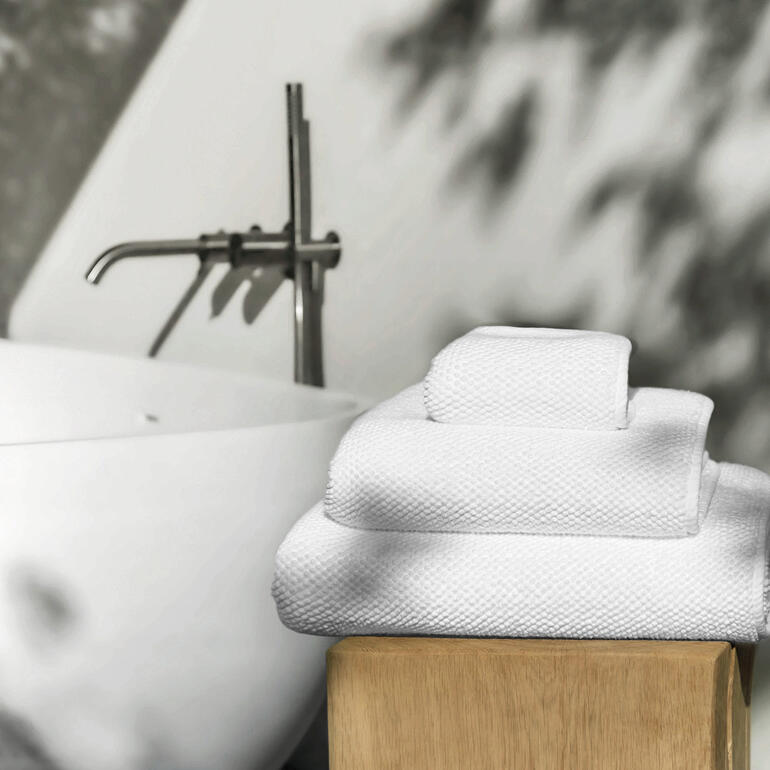 Serviettes de luxe Graccioza empilées sur un support en bois.