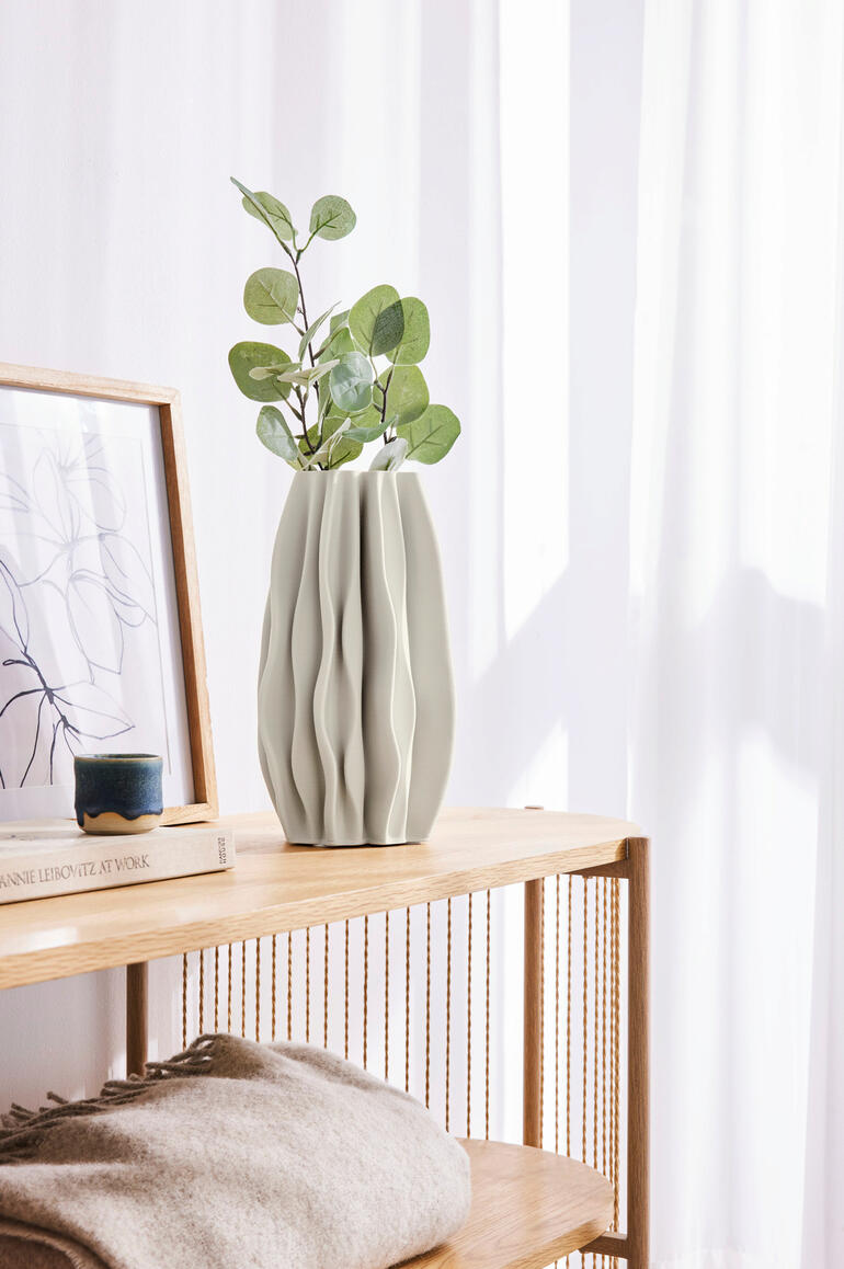 Vase en céramique imprimée en 3D avec plante sur une étagère.