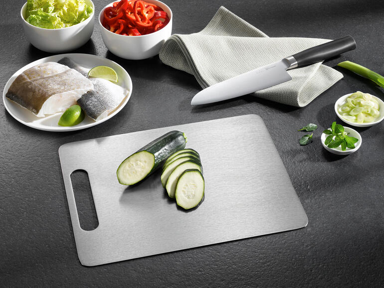 Planche à découper en titane avec des concombres coupés et d'autres ingrédients