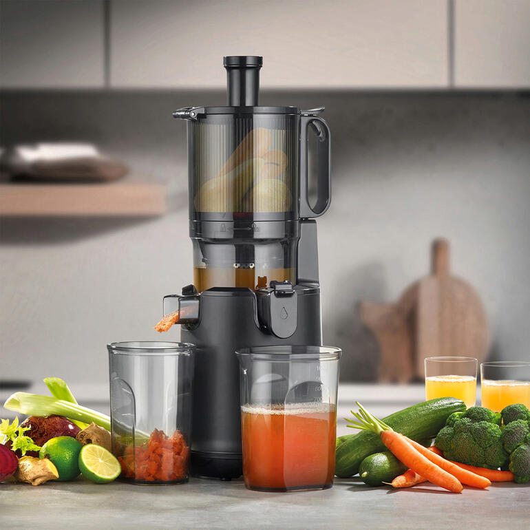 Extracteur de jus CASO Design avec des légumes frais et deux verres de jus sur une table