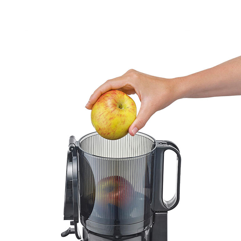 Main plaçant une pomme dans le compartiment supérieur de l'extracteur de jus CASO