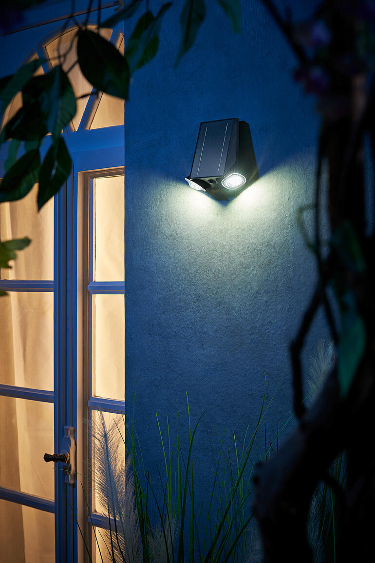 Lampe solaire intelligente sur un mur à côté d'une porte la nuit