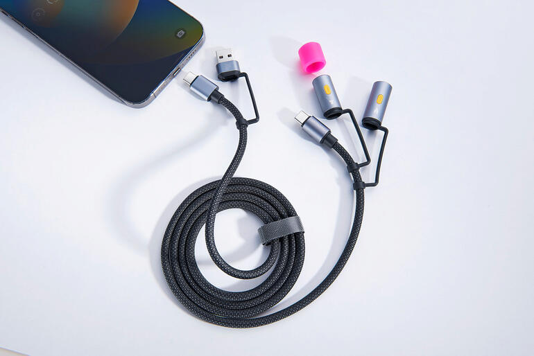 Câble de chargement 4-en-1 avec plusieurs options de connexion sur une table à côté d'un smartphone.