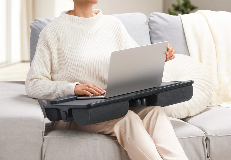 Personne avec un coussin pour ordinateur portable 2-en-1 sur les genoux, servant de table.