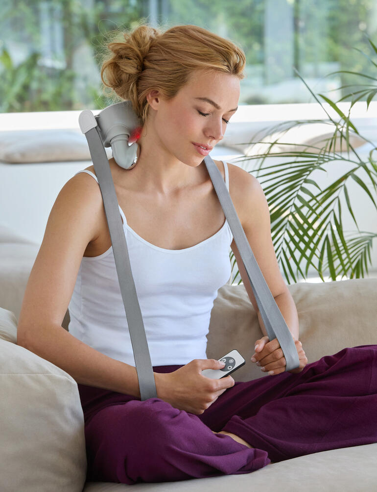 Femme utilisant un appareil de massage Shiatsu à 4 têtes sur le canapé.