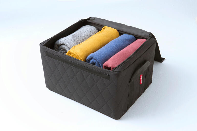 Boîte empilable noire avec des serviettes pliées colorées à l'intérieur.