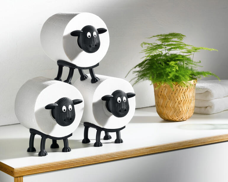 Trois porte-rouleaux de papier toilette en forme de moutons sur une table.