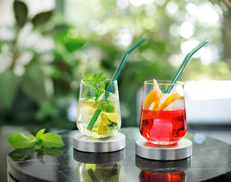Deux boissons avec des pailles vertes sur une table.