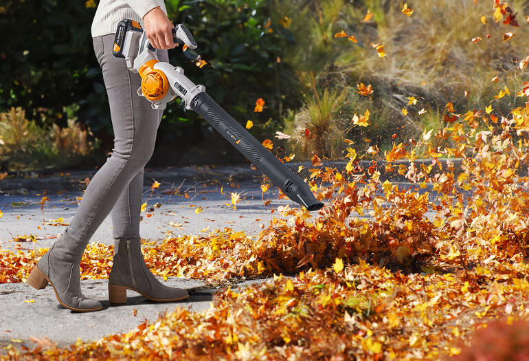 Personne utilisant un souffleur à feuilles à batterie dans le jardin