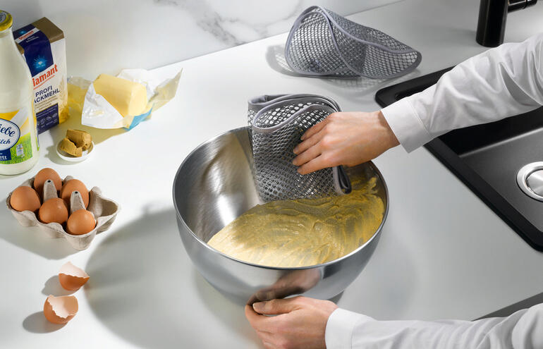 Deux chiffons de nettoyage à structure en maille à côté d'un bol de pâte.