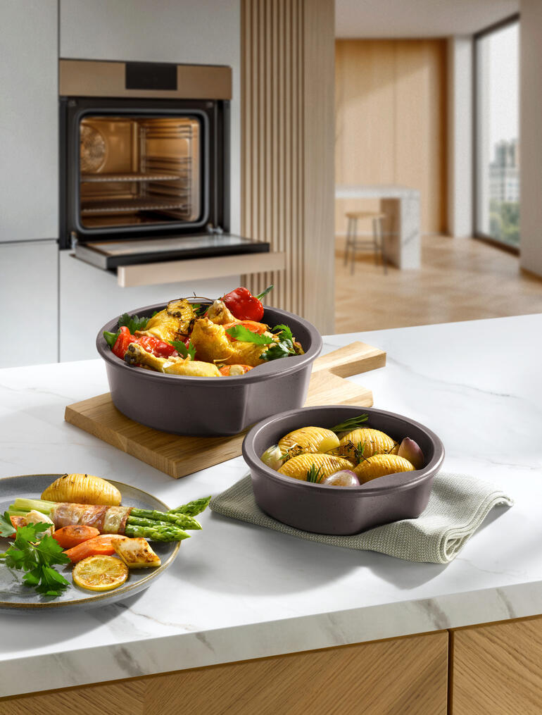 Deux pots celtes avec des légumes et des pommes de terre sur une assiette en bois dans une cuisine moderne.