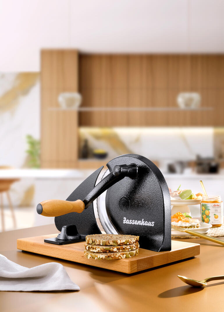 Trancheuse à pain manuelle sur une planche en bois avec du pain fraîchement tranché.