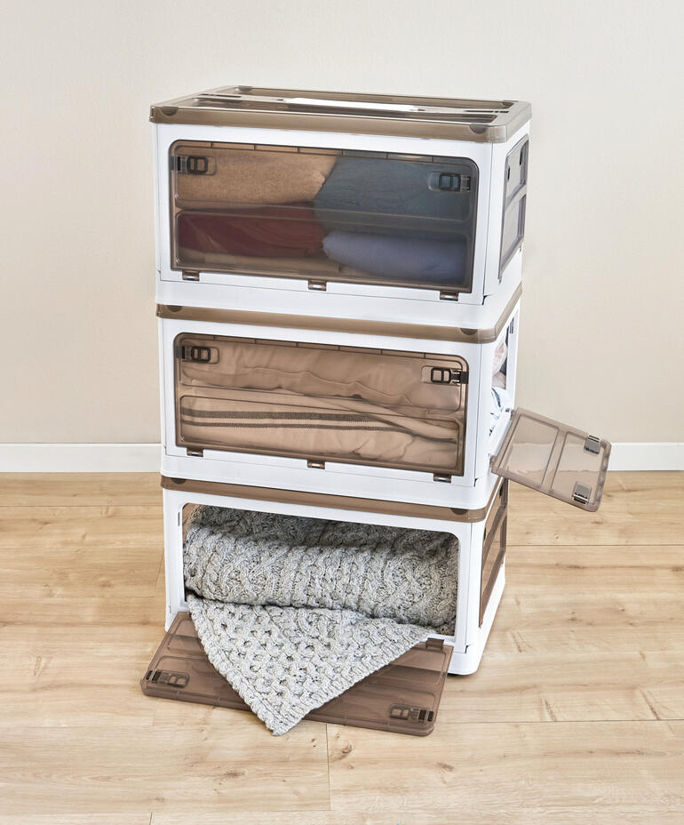Trois boîtes de rangement empilables avec des couvertures l'une sur l'autre.