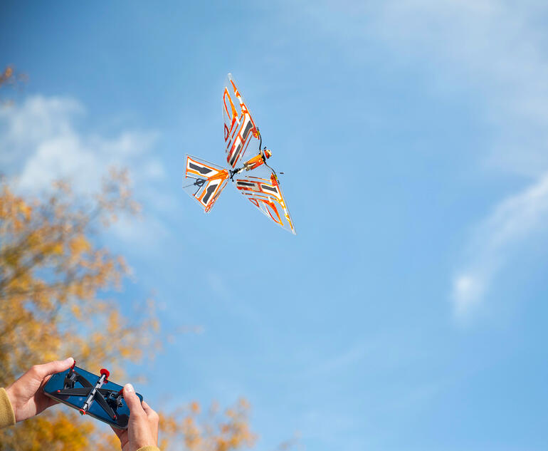 Ornithoptère télécommandé volant dans un ciel bleu avec un arrière-plan automnal.