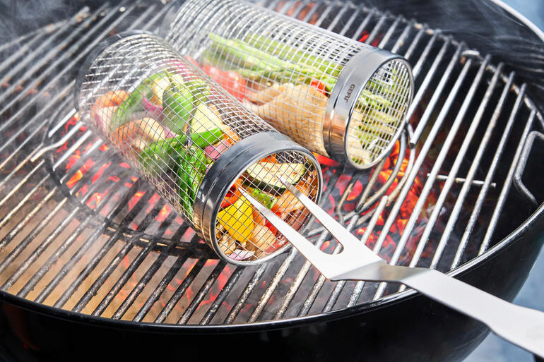 Panier à griller en métal avec des légumes, sur le gril avec des charbons ardents.