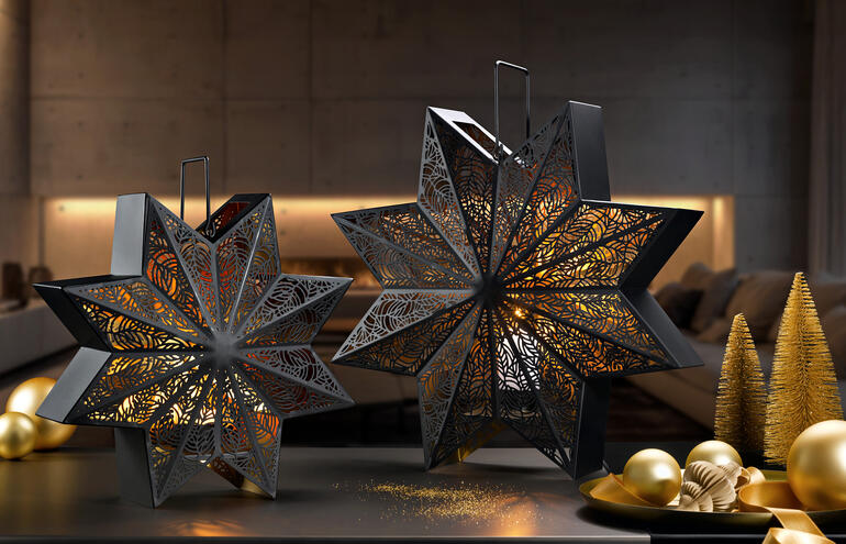 Deux lanternes décoratives en forme d'étoile sur une table avec des boules de Noël dorées.