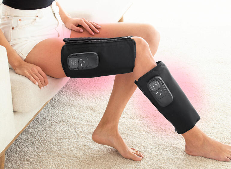 Femme avec un appareil de massage par compression sur les jambes assise.