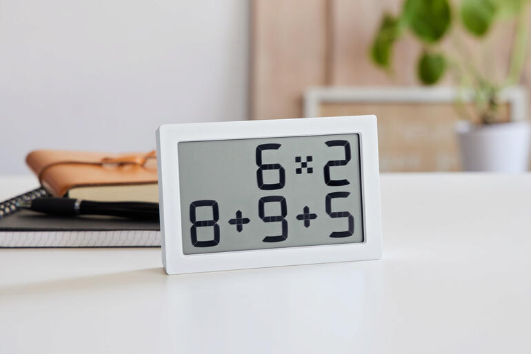 Horloge numérique affichant des opérations mathématiques en blanc.