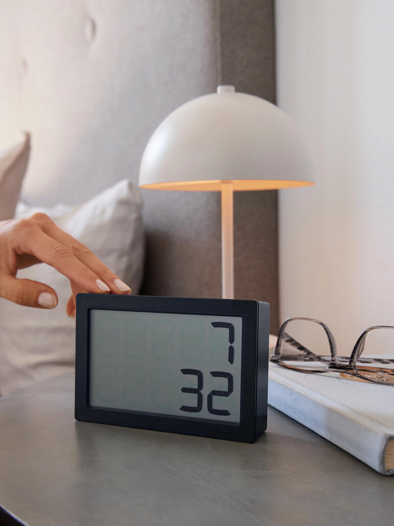 Main touchant l'horloge numérique 