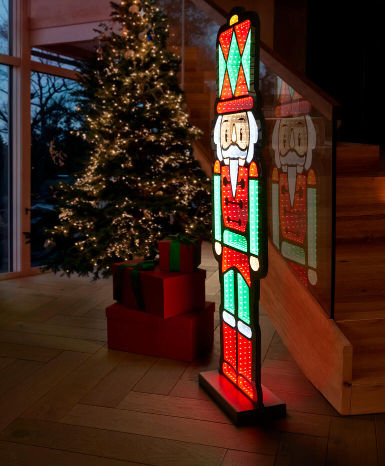 Sculpture LED d'un casse-noix devant un sapin de Noël.