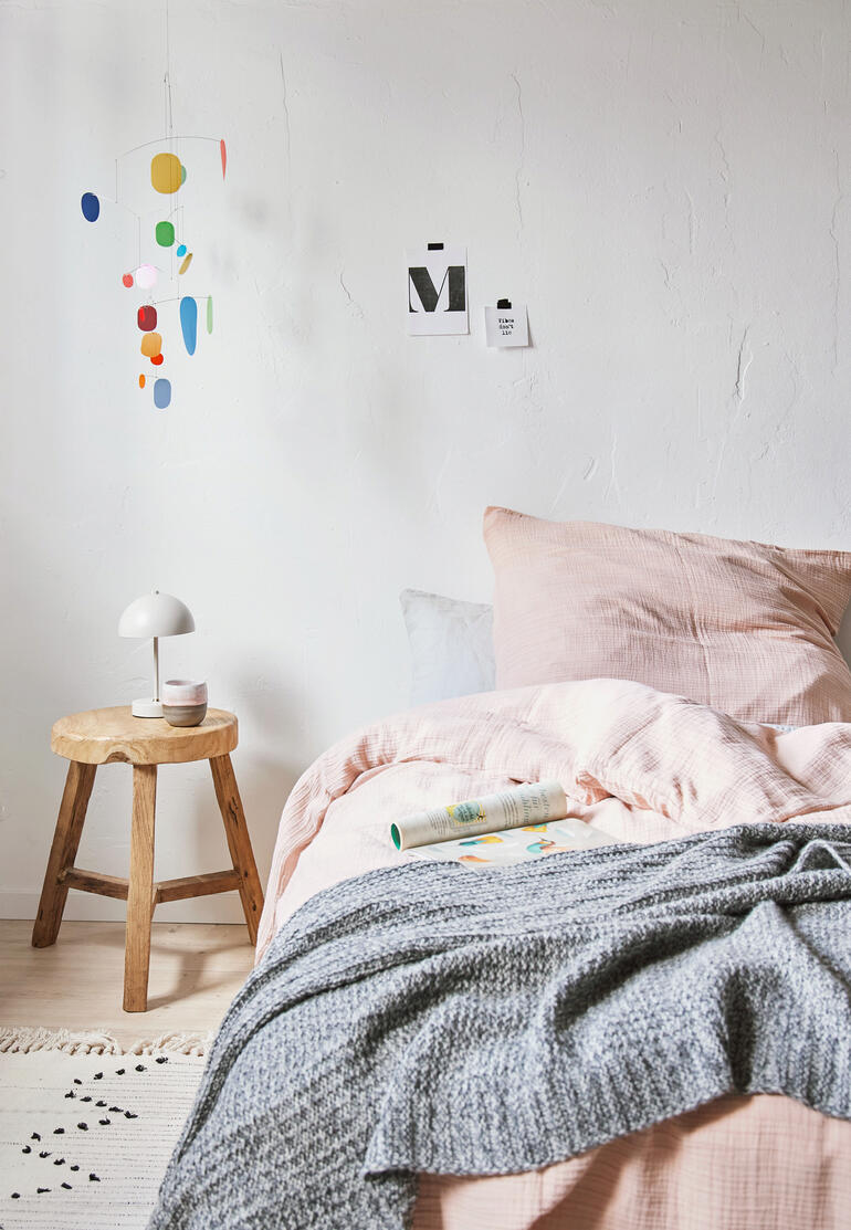 Un accroche-regard coloré et intemporel avec un message profond. Mobile d'avenir suspendu au-dessus d'un lit dans une chambre
