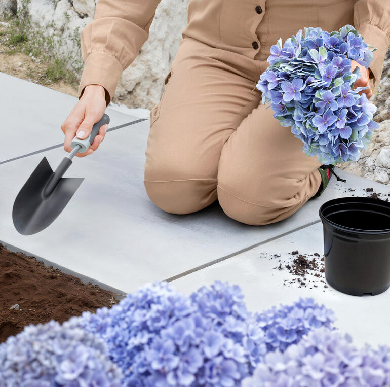 Genoux renforcés avec rembourrage inclus pour un travail confortable. Vue détaillée de fleurs dans les mains d'une femme.