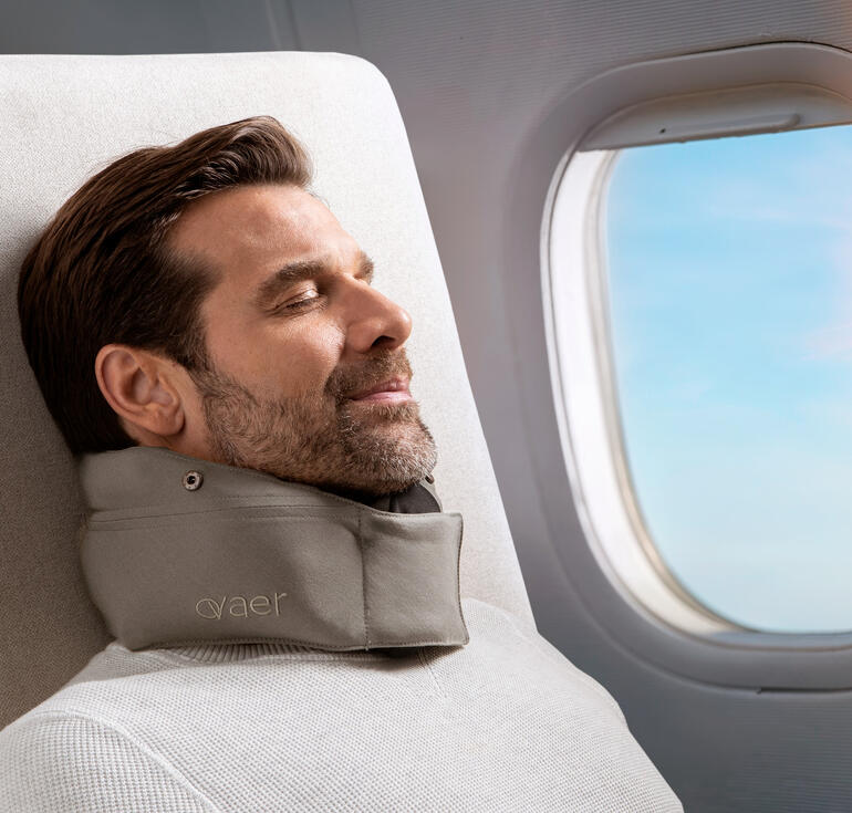 Homme avec un coussin de voyage se détend près de la fenêtre dans l'avion.