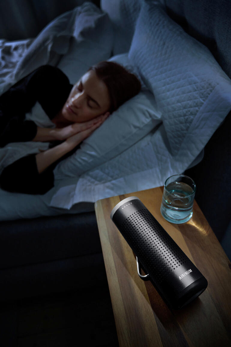 Purificateur d'air mobile 2-en-1 sur une table de nuit à côté d'une personne dormant
