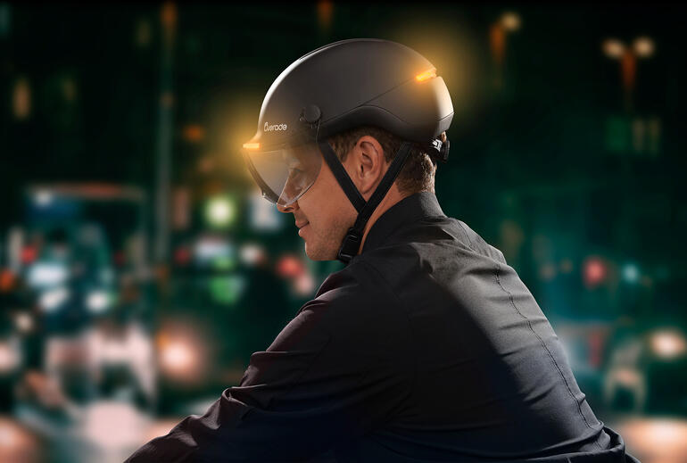 Homme portant un casque de vélo avec signal lumineux dans la ville la nuit